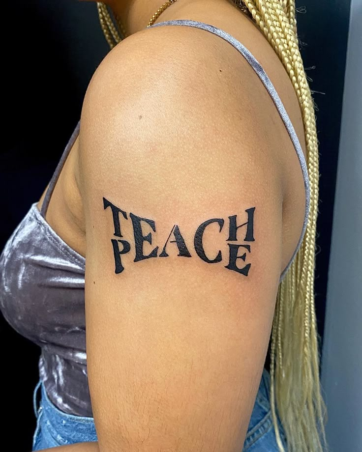 a woman with a tattoo on her arm that reads teach and has the word peace written across it