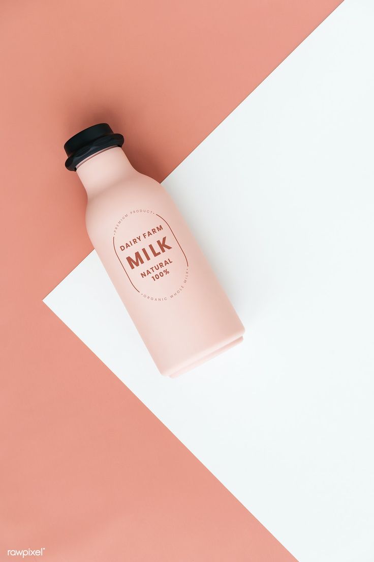 a bottle of milk sitting on top of a pink and white surface with a black cap