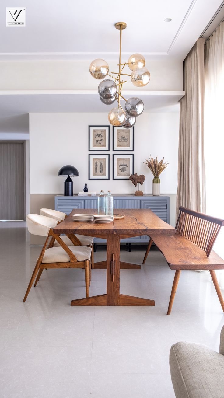 a dining room table and chairs in front of a window with pictures on the wall