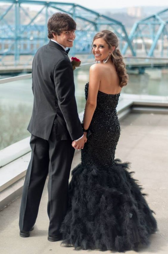 a man in a tuxedo standing next to a woman in a black dress