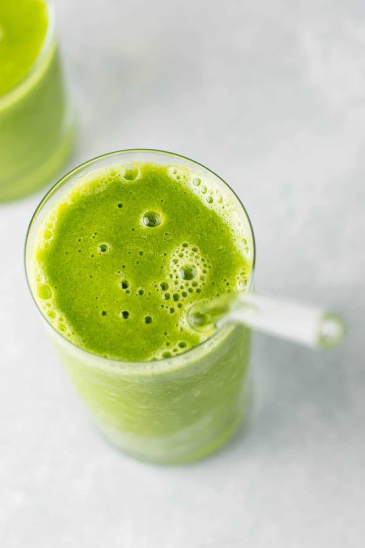 a green smoothie in a tall glass with a straw