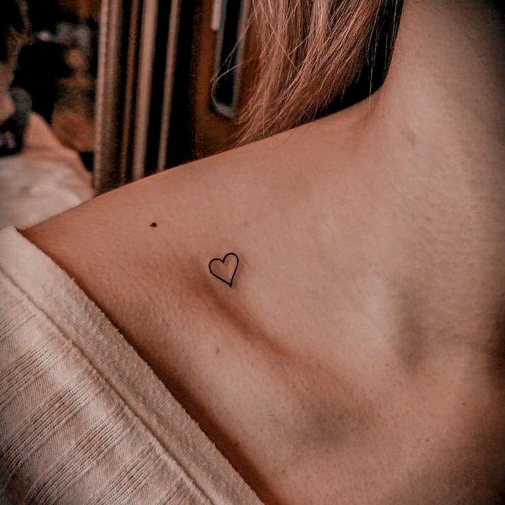 a woman with a small heart tattoo on her chest