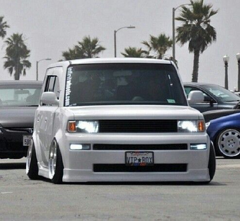 a white truck parked in a parking lot next to other cars and palm tree's