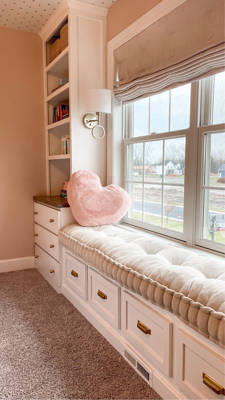 a window seat with a pink pillow on it