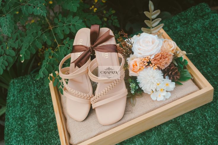 a pair of nude colored shoes sitting on top of a wooden box next to flowers