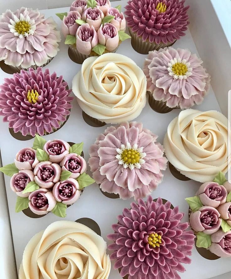 cupcakes decorated with pink and white flowers in a box