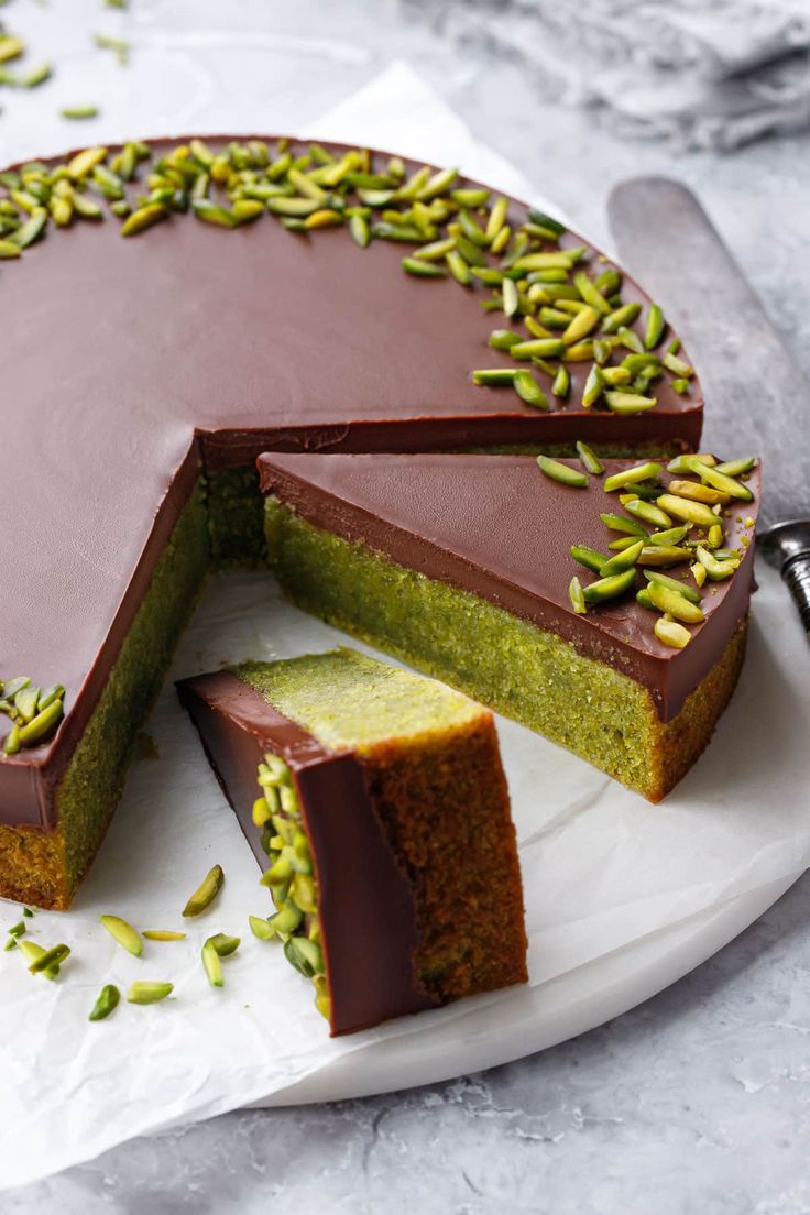 there is a chocolate cake with pistachios on the top and one slice missing