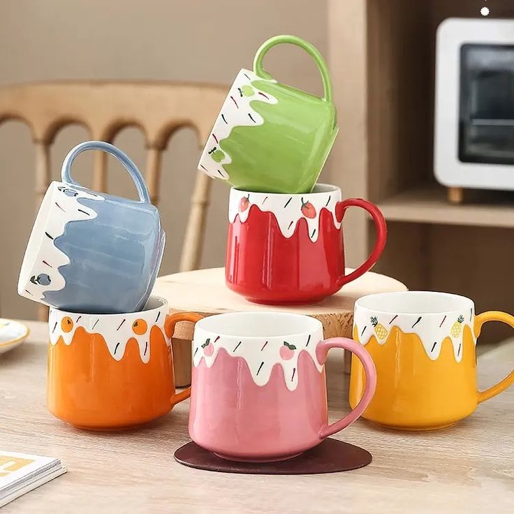 four coffee mugs are stacked on top of each other in front of a microwave