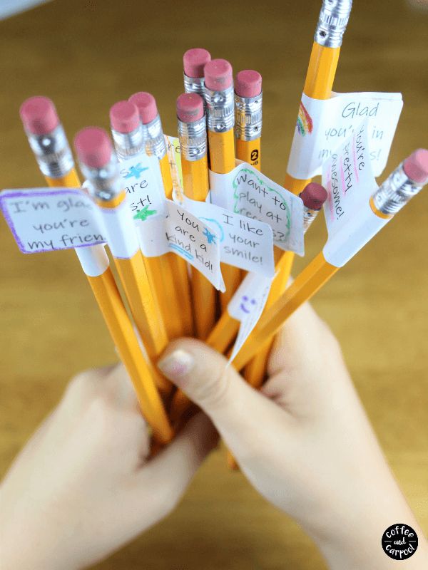 there are many pencils with writing on them in a cup that is held by someone's hand