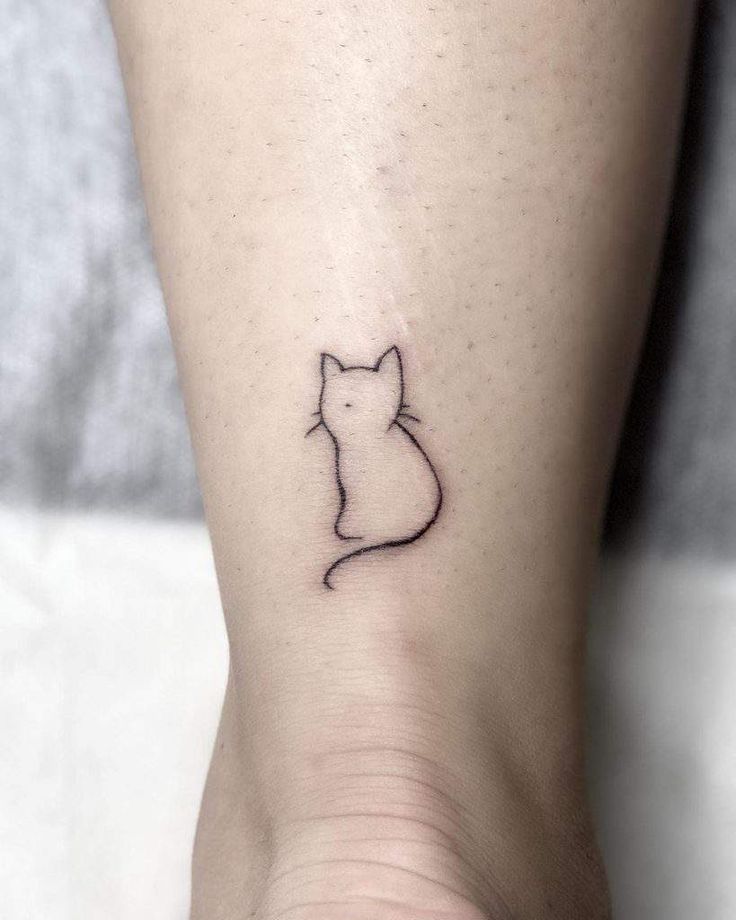 a small cat tattoo on the ankle is shown in black ink, and it has a tiny