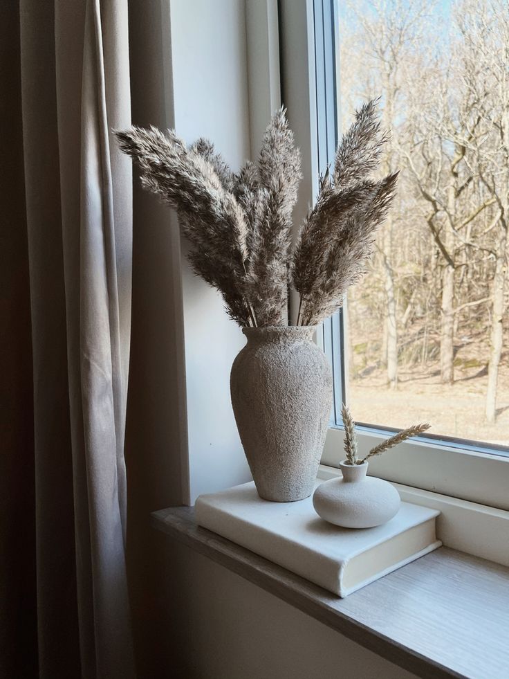 a plant in a vase sitting on top of a window sill