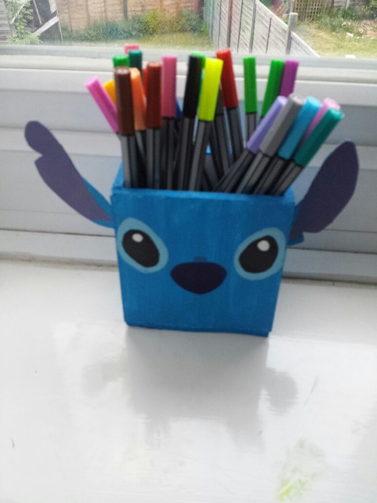 a blue container filled with markers and pens sitting on top of a window sill