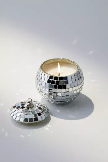 a candle that is sitting next to a mirror ball