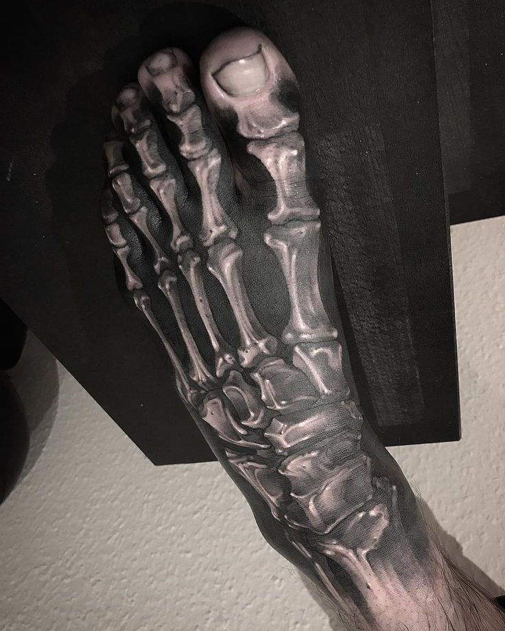 a man's foot with a skeleton tattoo on it