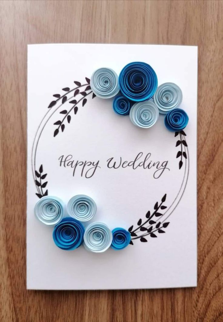 a card with blue paper flowers and the words happy wedding written in black on it