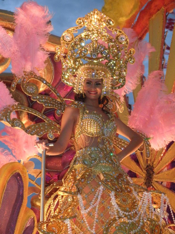 a woman in a gold and pink costume standing on top of a stage with lots of feathers