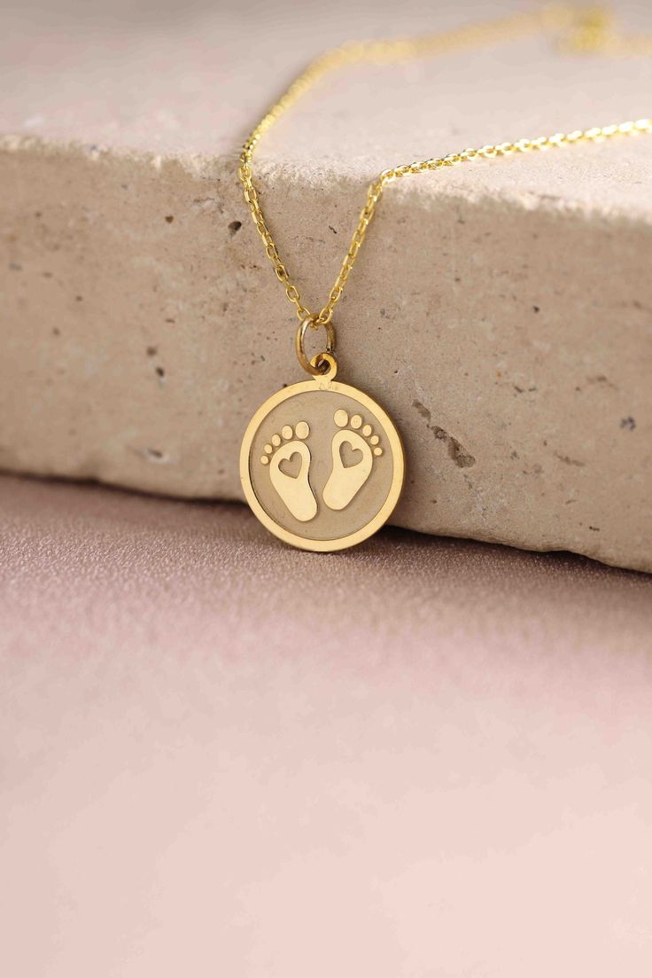 a gold necklace with a baby's footprints on it