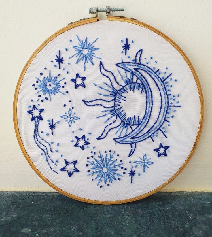 a blue and white embroidered sun and moon on a wall hanging in front of a stucco wall