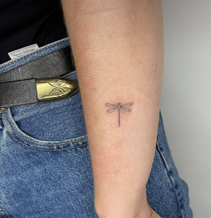 a small dragonfly tattoo on the arm