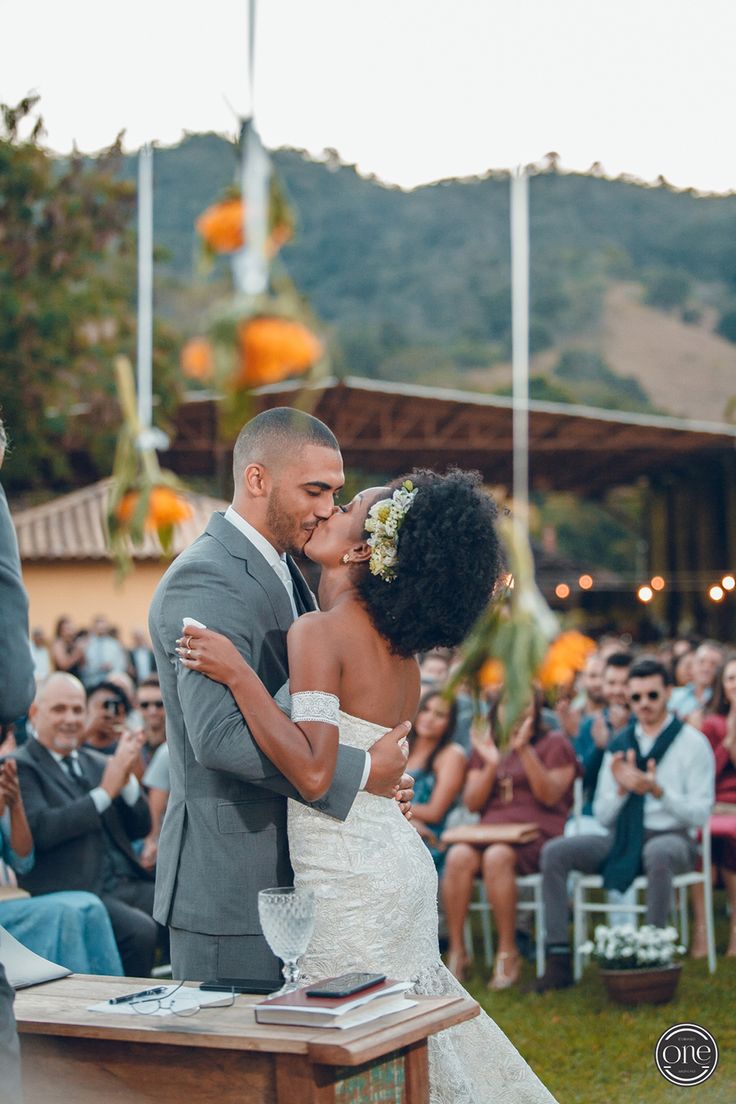 a bride and groom kissing in front of an outdoor wedding ceremony with people watching them