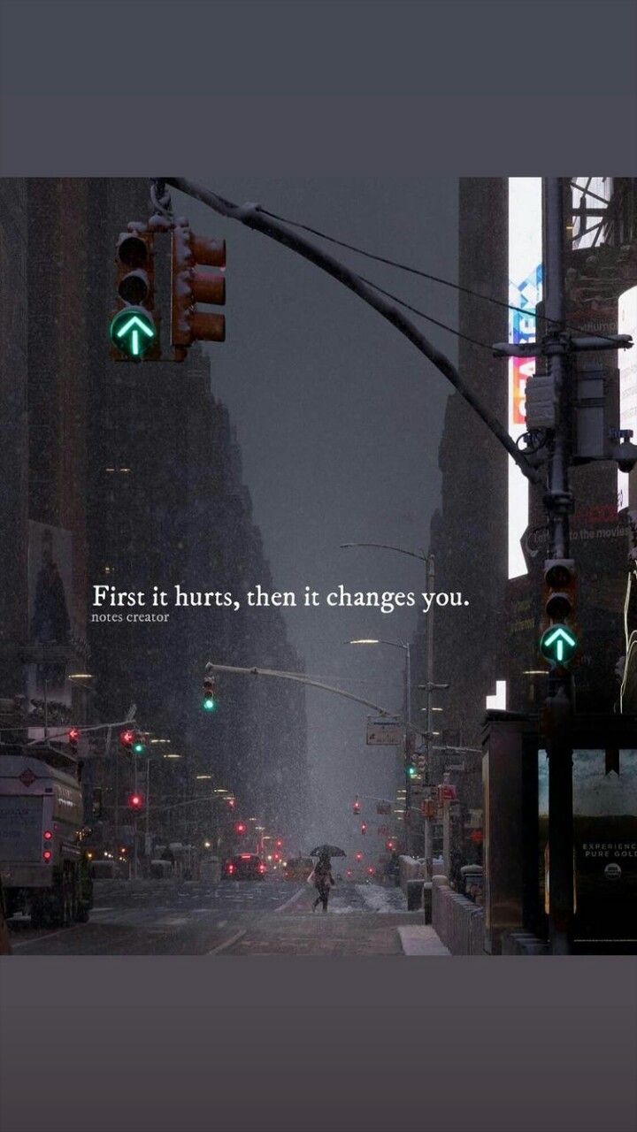 a city street with traffic lights and a person walking on the sidewalk in the rain