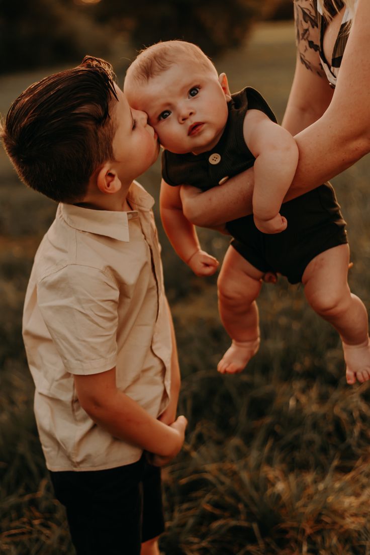 a man holding a baby up to his face as he kisses the child's cheek