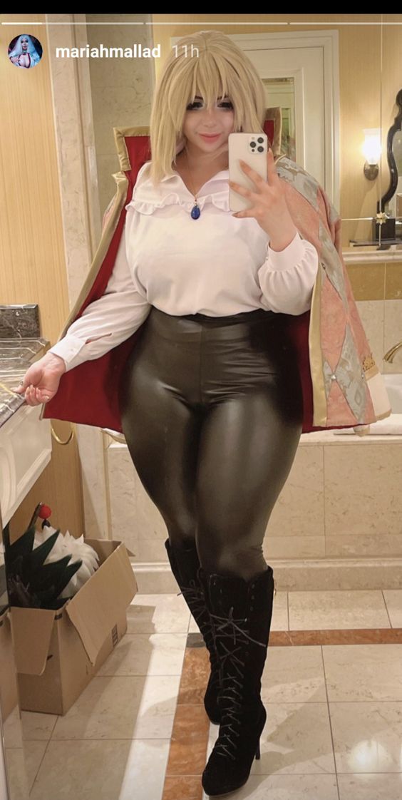 a woman is taking a selfie with her cell phone in the bathroom while wearing leather pants and boots