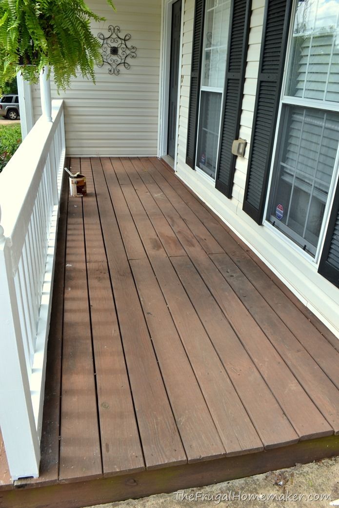 a wooden porch with white railing and black shutters