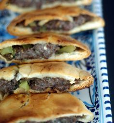 several pastries on a blue and white platter, with meat in the middle