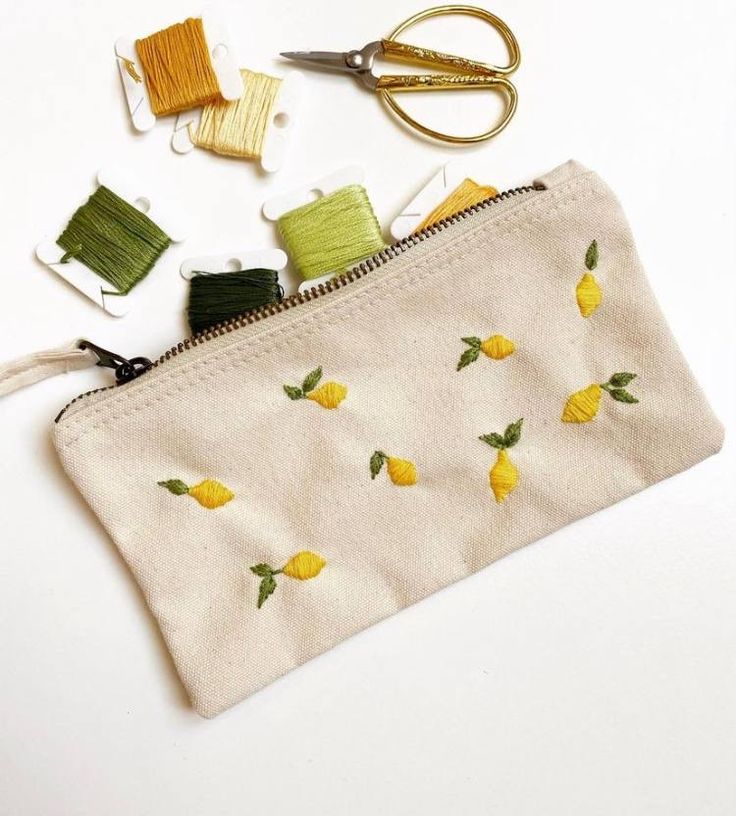 a zippered pouch with some sewing supplies on top of it, including scissors and thread spools