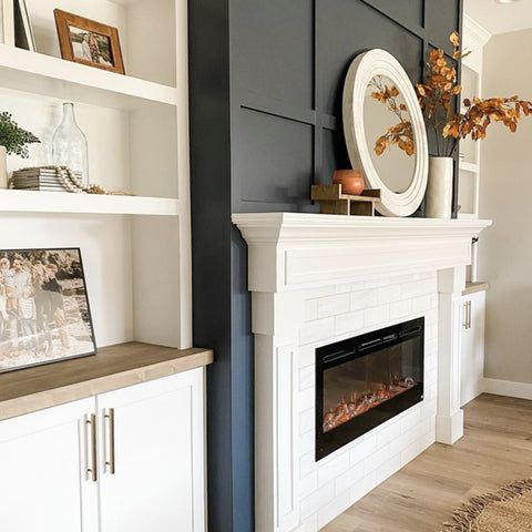 a living room with a fire place and white bookcases on the wall next to it