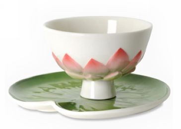 a white bowl with pink flowers sitting on top of a green saucer and plate