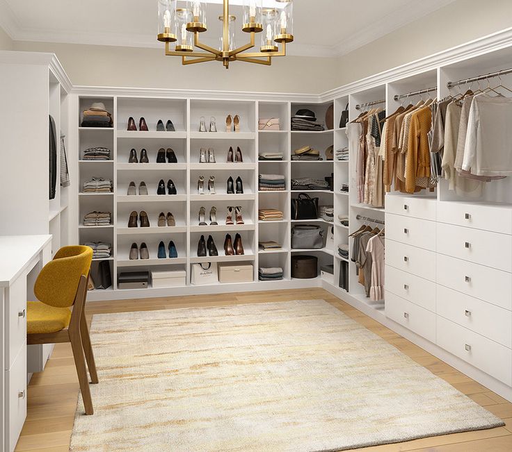 an organized closet with white shelving and gold chandelier