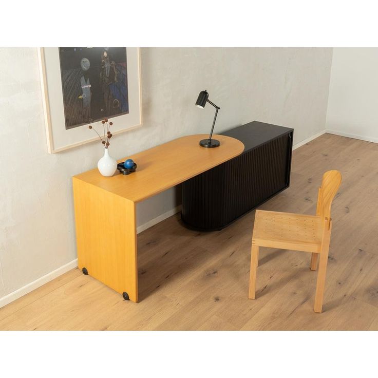 a wooden desk with a chair next to it and a painting hanging on the wall