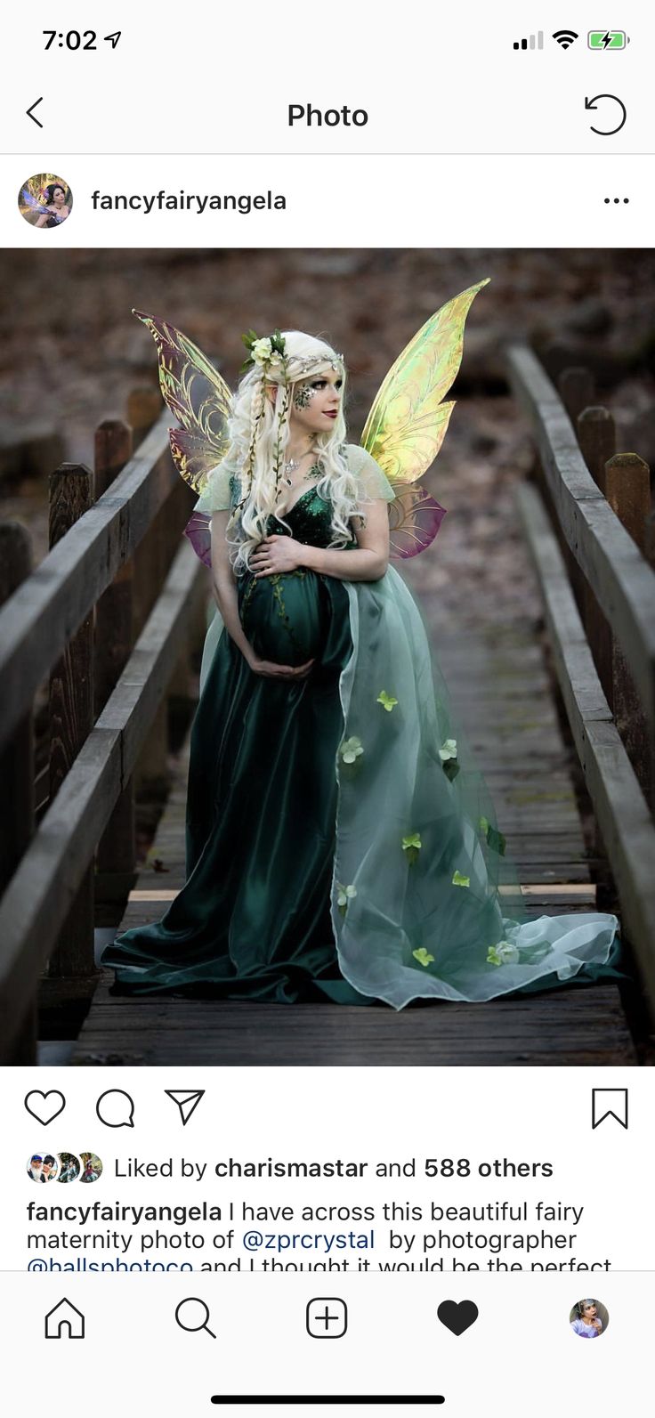 a woman dressed as a fairy sitting on top of a wooden bridge holding a baby