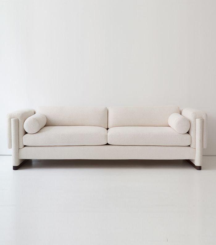 a white couch sitting on top of a hard wood floor next to a white wall