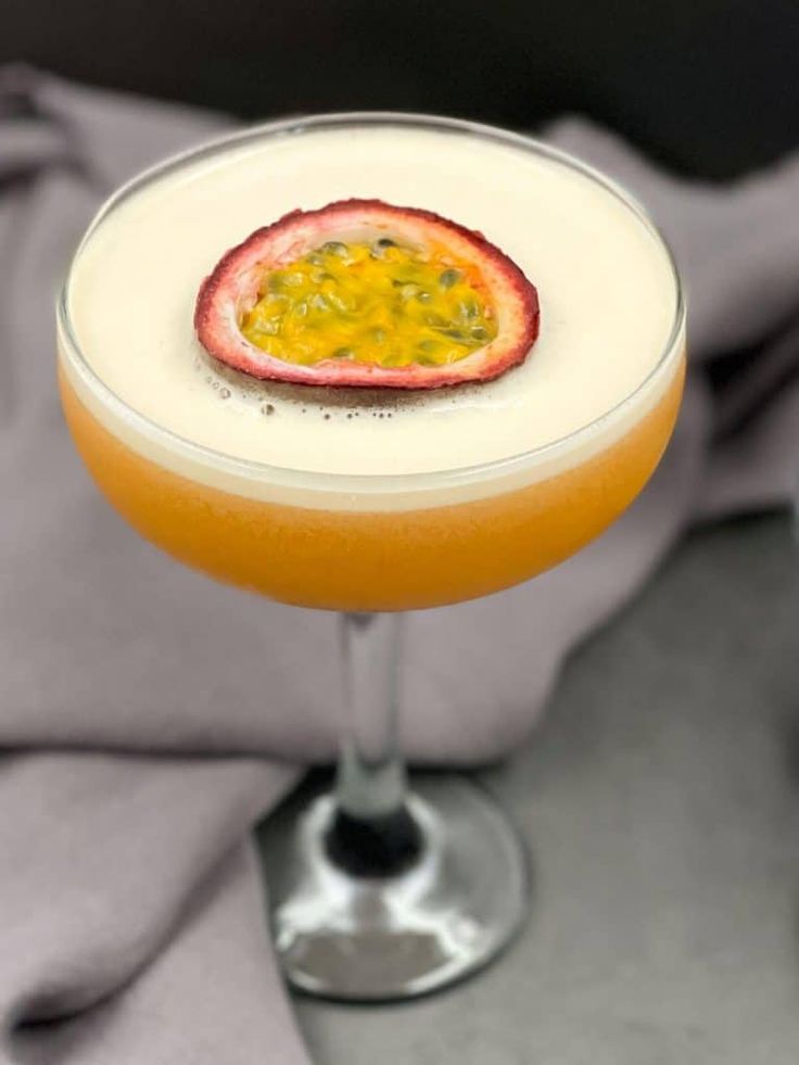 a drink in a glass with a fruit garnish on the rim