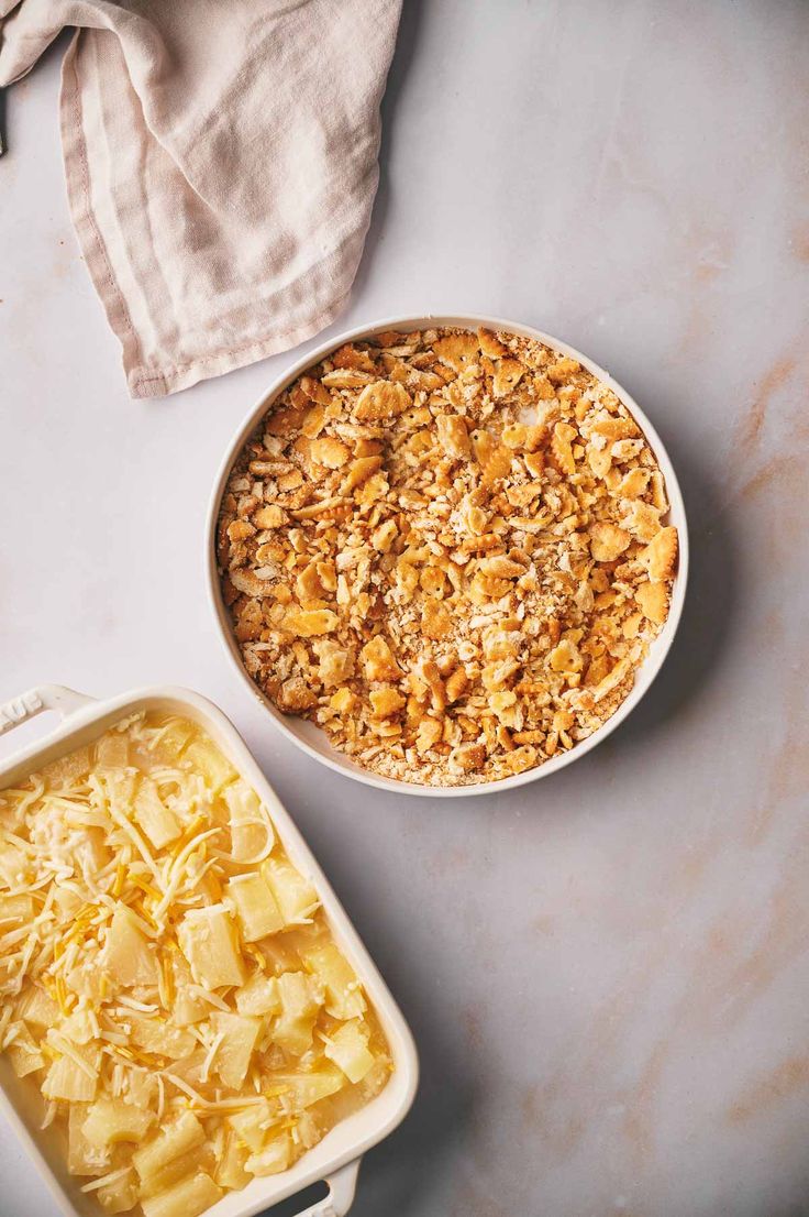 two bowls filled with food sitting on top of a counter next to a dish full of macaroni and cheese