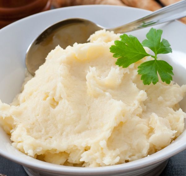 mashed potatoes in a white bowl with parsley garnish on the side