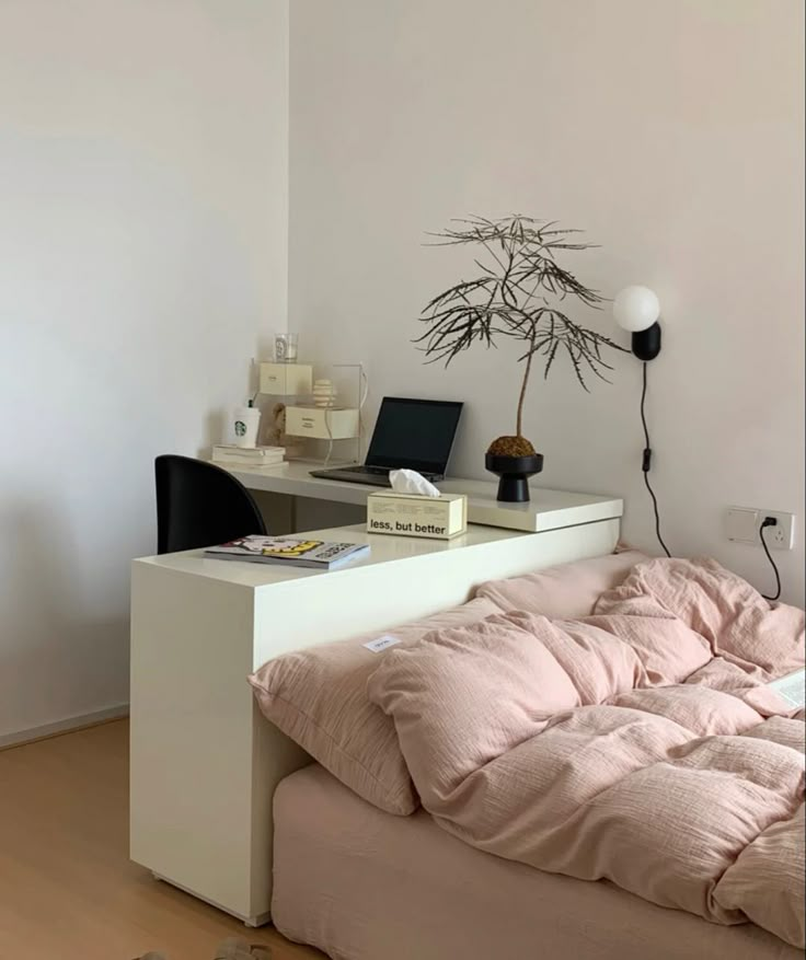 a bed with a pink comforter on top of it next to a computer desk