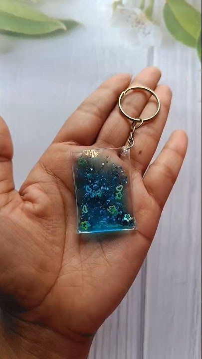 a hand holding a square shaped glass keychain