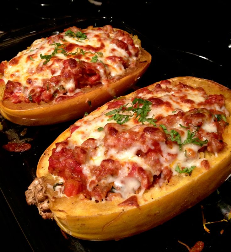 two stuffed sweet potatoes sitting on top of a stove with meat and cheese inside them