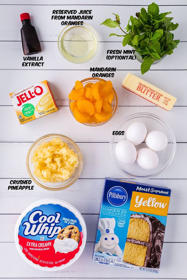 ingredients to make an easter cake laid out on a white wooden table with eggs, butter, yogurt and other items