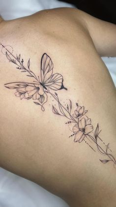 a woman with a butterfly tattoo on her back and shoulder, laying down in bed