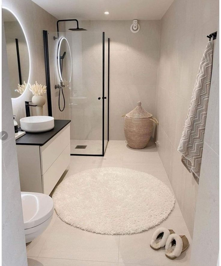 a bathroom with a white rug and black counter tops