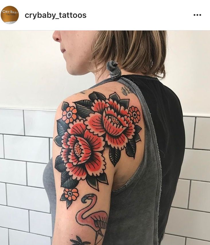 a woman with a flamingo and flowers tattoo on her arm is standing in front of a tiled wall