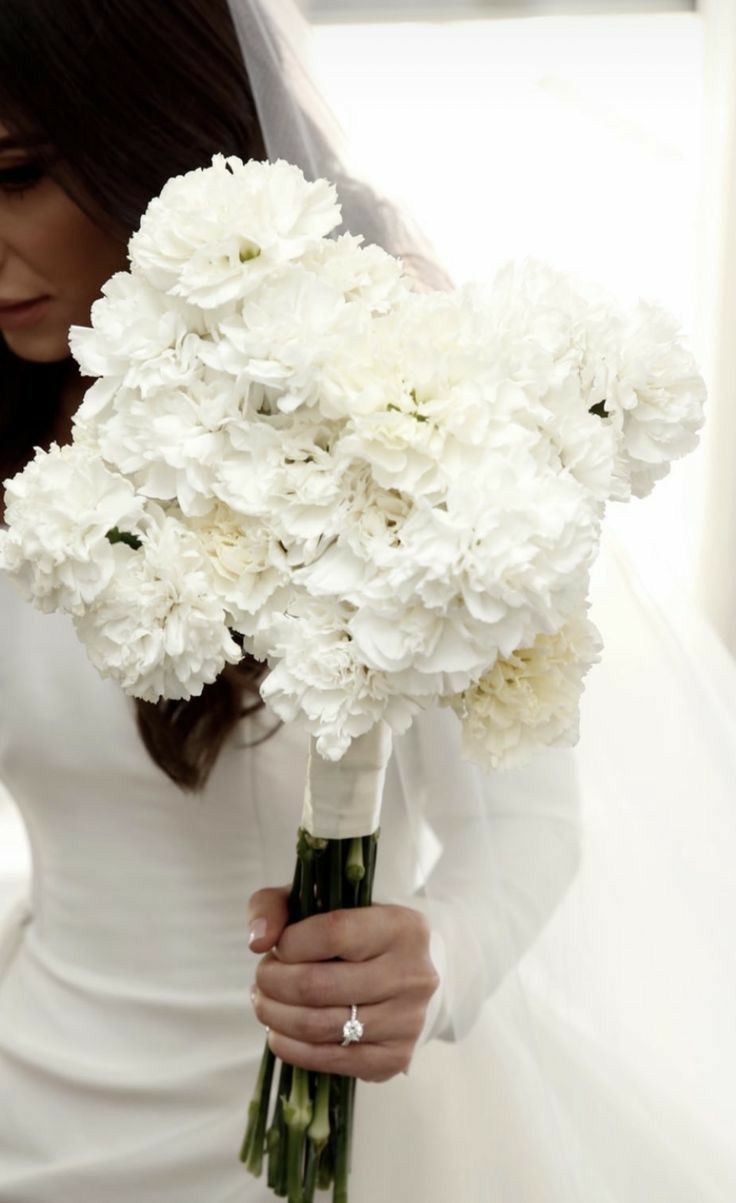 a bride holding a bouquet of white flowers