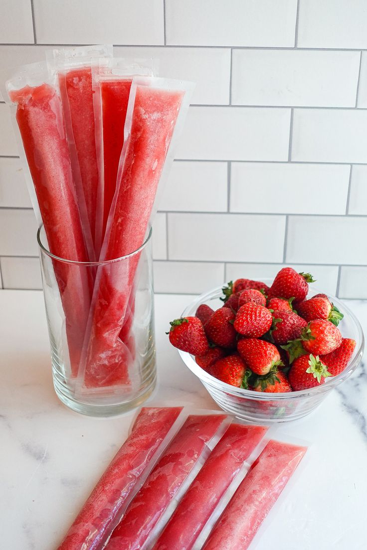 strawberries in plastic bags next to a bowl of strawberries