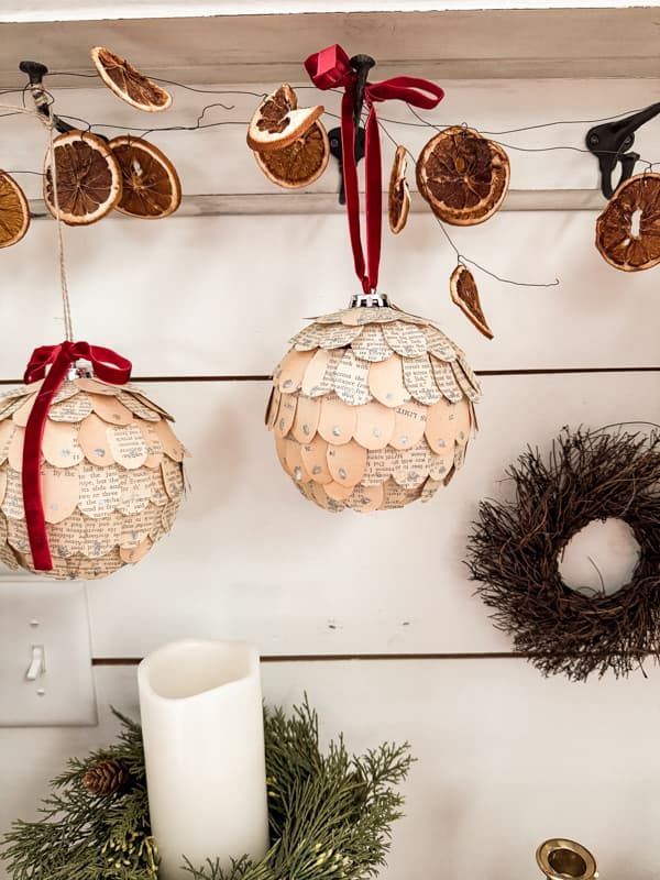 christmas decorations hanging from a wall with candles and wreaths on the shelf next to them