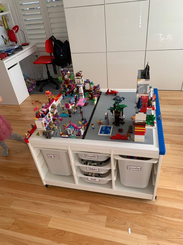 a table with legos on it in the middle of a room filled with toys